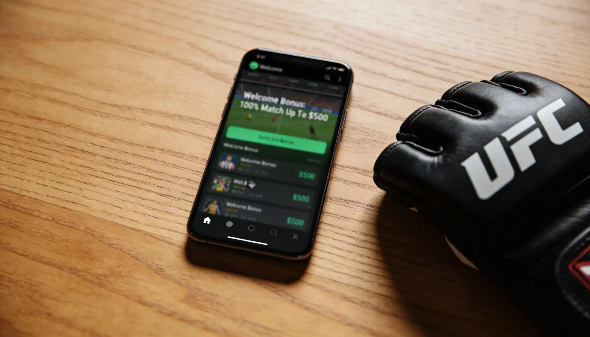Smartphone mit Sportwetten-App und MMA-Handschuhen auf einem Tisch